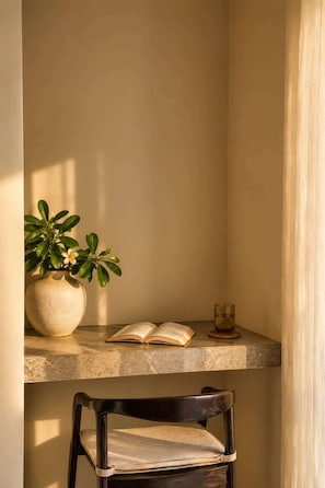 A corner of a room with a potted plant, an open book, and a glass of water on a shelf. - Villa Gaudi II (Kabupaten Badung)