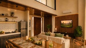 A modern kitchen with a dining area, a sofa set, and a large TV. - Villa Gaudi II (Kabupaten Badung)