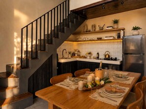 Eine moderne Küche mit Essbereich, gedeckt für eine Mahlzeit, inklusive Treppe, Küchenarbeitsplatte und Kühlschrank.