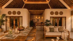 A dining area with a long wooden table set for a meal, surrounded by chairs. - Villa Juma (Kabupaten Badung)