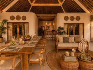 A dining area with a long wooden table set for a meal, surrounded by chairs. - Villa Juma (Kabupaten Badung)