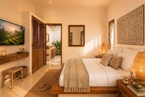 A bedroom with a bed, bedside table, lamp, and a painting on the wall. - Villa Juma (Kabupaten Badung)