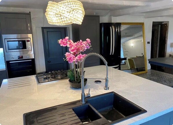 A modern kitchen with a built-in microwave, a gas stove, a sink, and a stainless steel refrigerator.