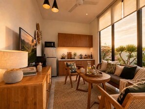 A modern kitchen with wooden cabinets, a dining area with a round table, and a sofa with cushions. - Villa Hibiscus I (Kabupaten Badung)