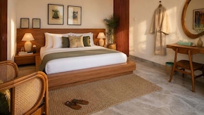 A hotel room with a large bed, bedside tables, a desk, a chair, a mirror, and framed artwork on the wall. - Villa Hibiscus I (Kabupaten Badung)