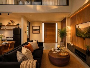 A modern living room with a black sofa, a round coffee table, and a TV mounted on the wall. - Villa Gaudi I (Kabupaten Badung)