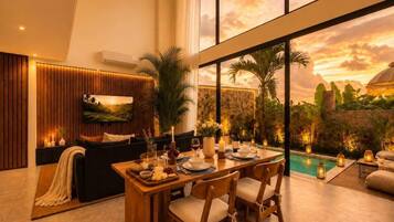 A modern interior with a dining area, a sofa, and a view of a pool.