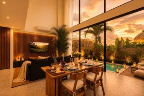 A modern interior with a dining area, a sofa, and a view of a pool. - Villa Gaudi I (Kabupaten Badung)