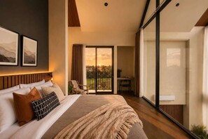Ein Schlafzimmer mit einem großen Bett, einem Schreibtisch und einem Balkon mit Blick.