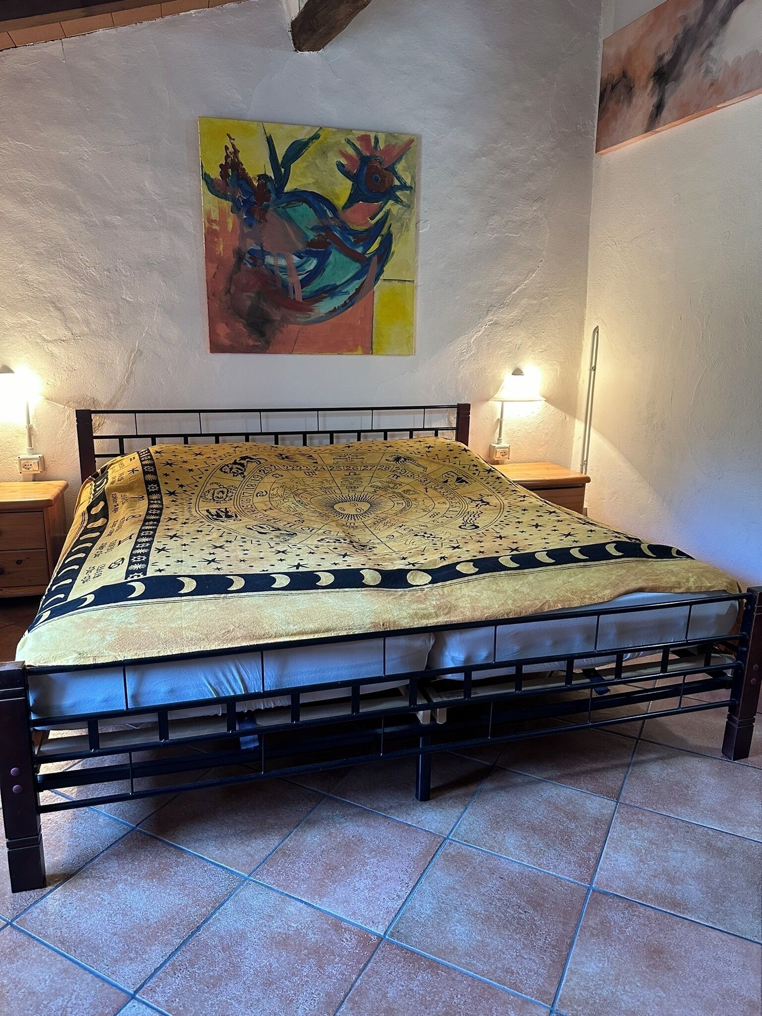 Une chambre à coucher avec un lit, une table de chevet, une lampe et un tableau au mur.