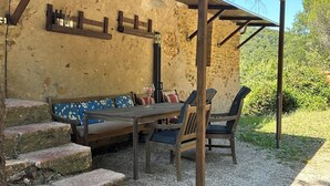 Un espacio de estar rústico al aire libre con pared de piedra, bancos de madera y suelo de grava.