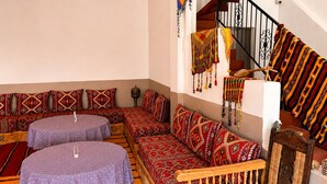 A room with a sofa set, a wooden bench, and a staircase with a railing. - Auberge Restaurant Zahra (Ait Sedrate Jbel El Soufla)