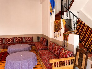 A room with a sofa set, a wooden bench, and a staircase with a railing. - Auberge Restaurant Zahra (Ait Sedrate Jbel El Soufla)