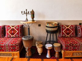 Una habitación con sofás de estampado tradicional, una mesita con un candelabro y una colección de tambores.