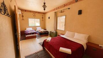 A hotel room with two beds, a large window, a decorative ceiling, and a small table.