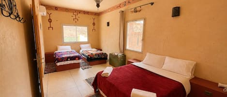 A hotel room with two beds, a large window, a decorative ceiling, and a small table.