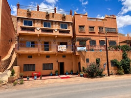 Un edificio de varios pisos con balcones, un letrero de restaurante y plantas en macetas.