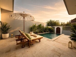 Ein Poolbereich mit Liegestühlen, einer Pergola mit hängenden Lichtern und Kübelpflanzen.