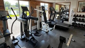 A gym with cardio machines, weightlifting equipment, and a mirror reflecting the equipment. - Lochside Perthshire Lodge for 4 (Perth)