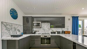 A modern kitchen with a marble countertop, stainless steel appliances, and a wooden floor. - Lochside Perthshire Lodge for 4 (Perth)