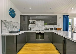 A modern kitchen with a marble countertop, stainless steel appliances, and a wooden floor. - Lochside Perthshire Lodge for 4 (Perth)