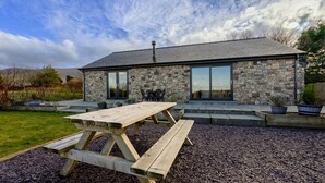 A stone house with a large patio table and outdoor seating. - Cosy Aberdeenshire Stone Cottage (Caernarfon)