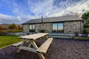 A stone house with a large patio table and outdoor seating. - Cosy Aberdeenshire Stone Cottage (Caernarfon)