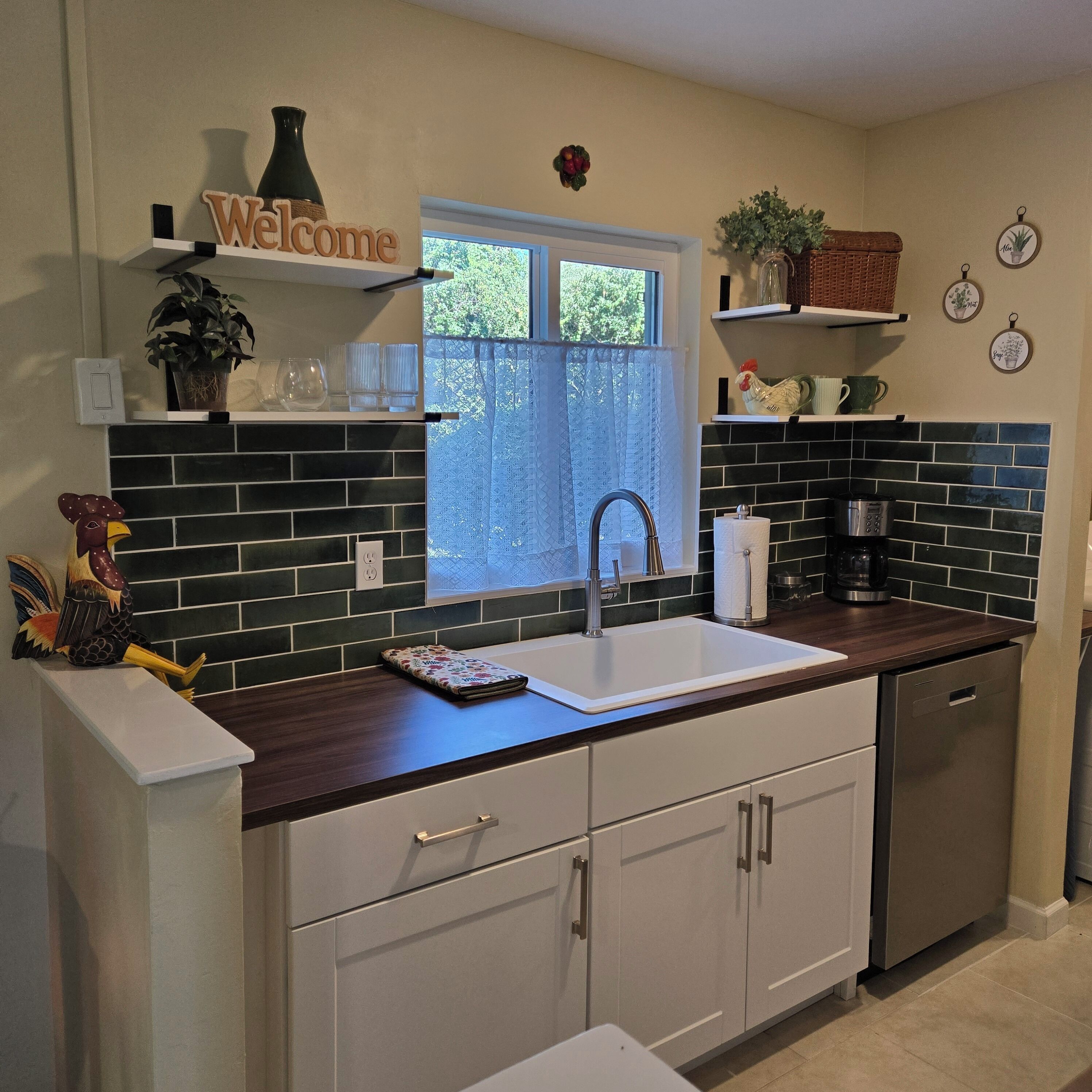 Una cocina moderna con un lavamanos blanco, salpicadero oscuro y armarios de madera.