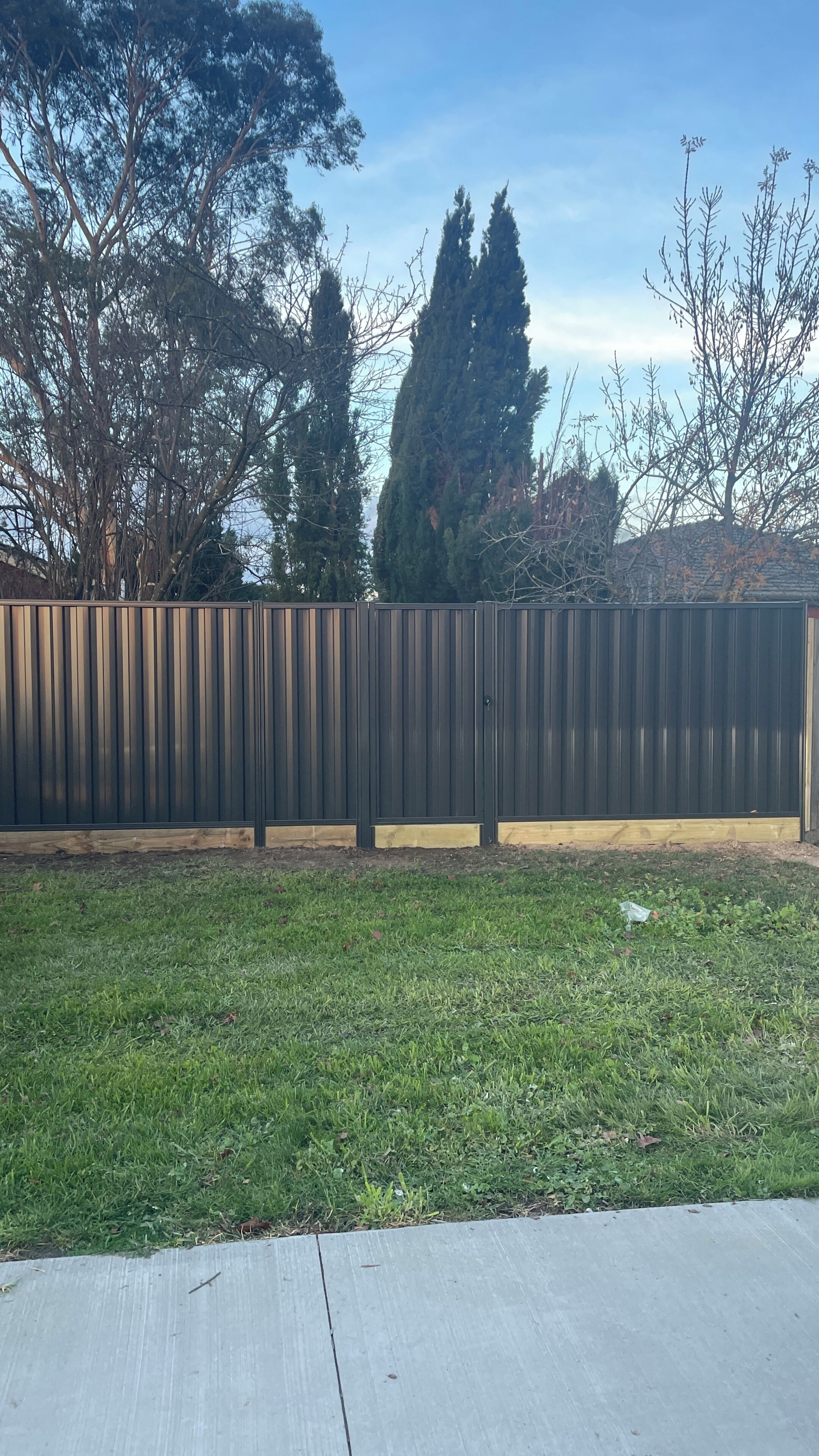 A fenced yard with a grassy area and trees in the background.