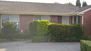 A residential house with a tiled roof, brick walls, and a well-maintained hedge. - Donvale holiday home  relaxing .15 minutes drive to CBD one minute walk to bus s (Donvale)