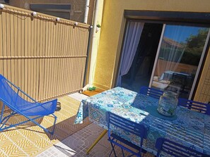 Eine Terrasse im Freien mit Tisch und Stühlen, einer Schiebetür und einem Holzzaun.