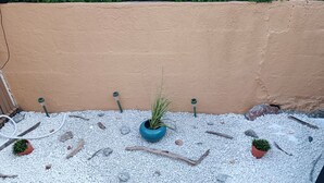 A wooden deck with a gravel area, potted plants, and a wall. - Beautiful 2-Bedroom Townhouse, Frontignan, Secure Residential Complex, Beach Access 100 m Away (Frontignan)