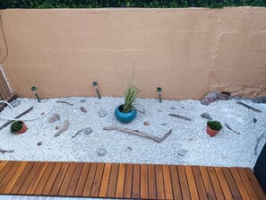 A wooden deck with a gravel area, potted plants, and a wall. - Beautiful 2-Bedroom Townhouse, Frontignan, Secure Residential Complex, Beach Access 100 m Away (Frontignan)