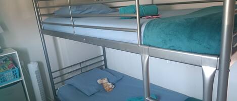 A bunk bed with a white fan and a small shelf unit.