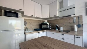 A modern kitchen with white cabinetry, a wooden countertop, a microwave, a coffee maker, and a built-in oven. - Beautiful 2-Bedroom Townhouse, Frontignan, Secure Residential Complex, Beach Access 100 m Away (Frontignan)