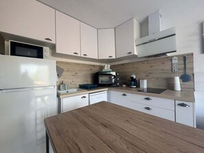 A modern kitchen with white cabinetry, a wooden countertop, a microwave, a coffee maker, and a built-in oven. - Beautiful 2-Bedroom Townhouse, Frontignan, Secure Residential Complex, Beach Access 100 m Away (Frontignan)