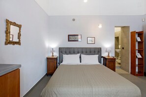 A hotel room with a large bed, two bedside tables with lamps, a wooden wardrobe, a mirror, and framed pictures on the wall. - La Dimora Dei Reali - Grey Suite with Balcony, Wi-Fi and Air Conditioning (Naples)