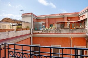 Une terrasse sur le toit, dotée d’une rambarde en métal, d’une structure vitrée et offrant une vue sur les bâtiments adjacents.