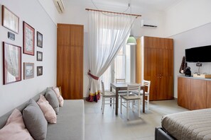 Une chambre moderne comprenant un lit, un canapé, une table à manger avec des chaises, un téléviseur et une armoire.