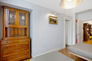 Ein Flur mit einem Holzkabinett, einem gerahmten Gemälde und einem Bett.