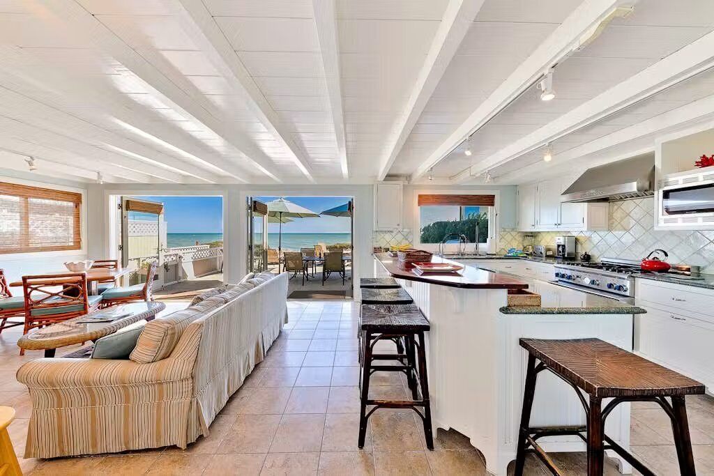 Amplia sala de estar con sofá, mesa de comedor y cocina con una isla grande.