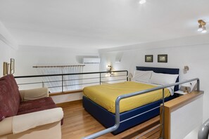 A modern hotel room with a bed, a seating area, and a view of the sea. - La Dimora Dei Reali – Yellow Suite with Wi-Fi and Air Conditioning (Naples)