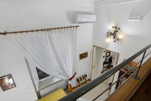 Ett rum med en vit luftkonditioneringsenhet, ett duschdraperi, en spegel och en väggmonterad lampa.