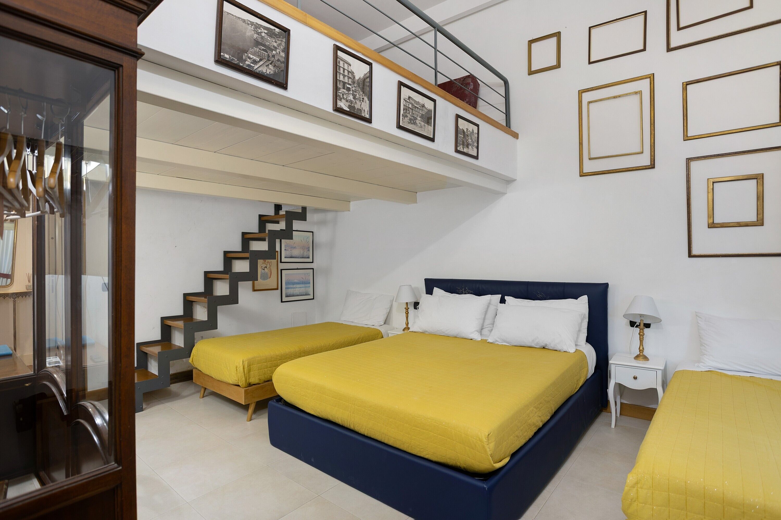 Ein Schlafzimmer mit zwei Betten, einer Treppe und einer Erkerwohnung mit gerahmten Bildern.