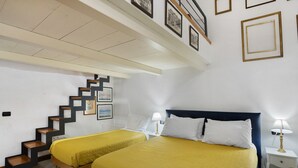 Ett hotellrum med två sängar, en trappa och inramade tavlor på väggarna.