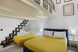 Ein Hotelzimmer mit zwei Betten, einer Treppe und gerahmten Bildern an den Wänden.