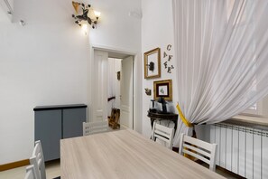 A dining area with a table, chairs, a cabinet, and a wall-mounted light fixture. - La Dimora Dei Reali – Yellow Suite with Wi-Fi and Air Conditioning (Naples)