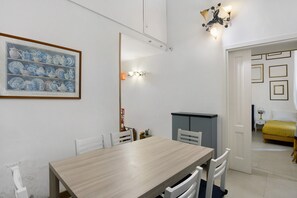 Un coin repas avec une table et des chaises en bois, une œuvre d’art encadrée au mur et un luminaire suspendu au plafond.
