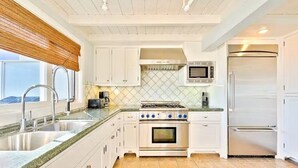 A modern kitchen with white cabinets, a stainless steel refrigerator, a microwave, a stove, and a sink. - On The Sand, Perfect 4 Families, Endless Sunset Views! (Dana Point)