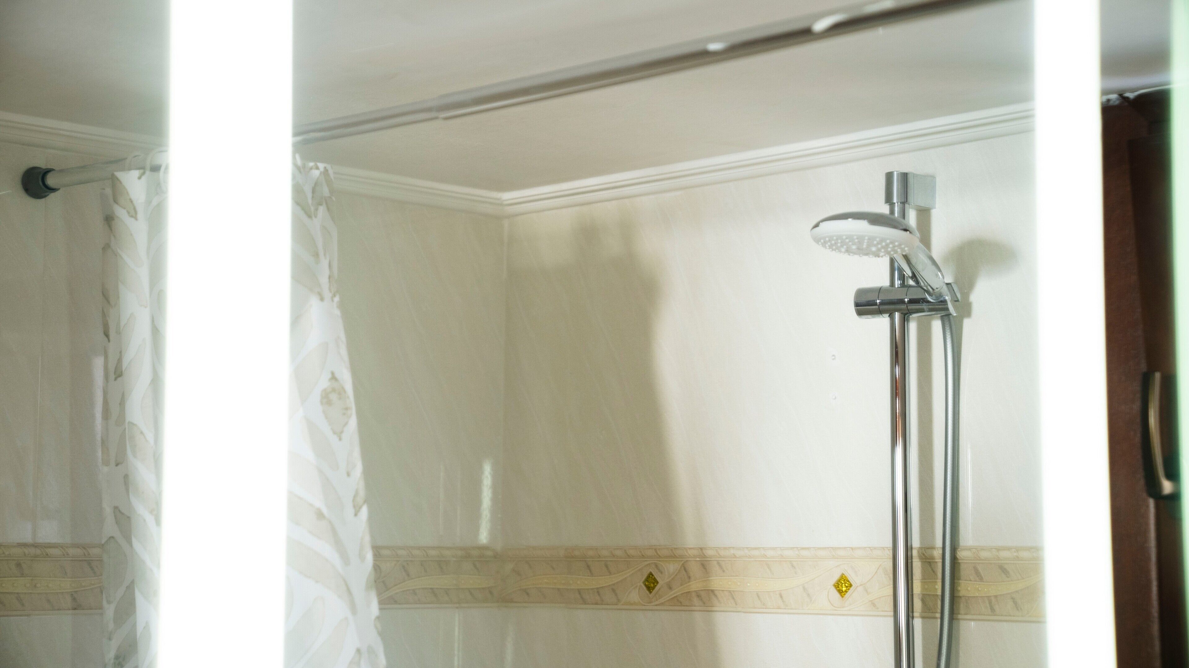 A bathroom with a shower, a curtain, and a decorative border on the wall.